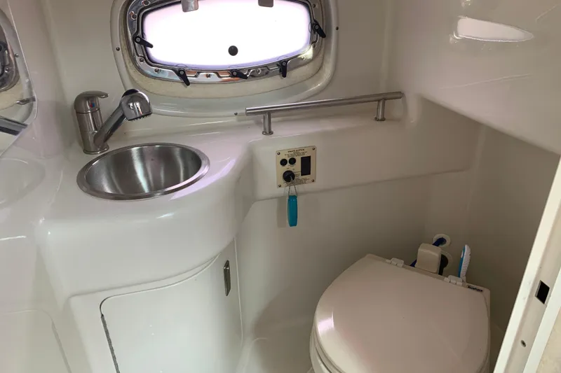 Slide: The Image of 2010 Sea Ray 260 Sundancer bathroom with sink, toilet, and porthole window. - 51