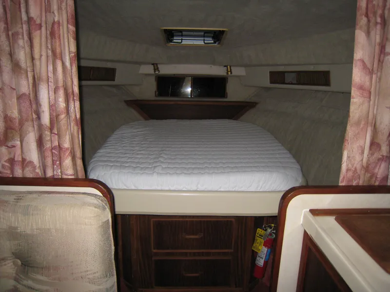 Slide: The Image of 1986 Sea Ray 340 Express Cruiser cabin with bed, wood accents, and floral curtains. - 10