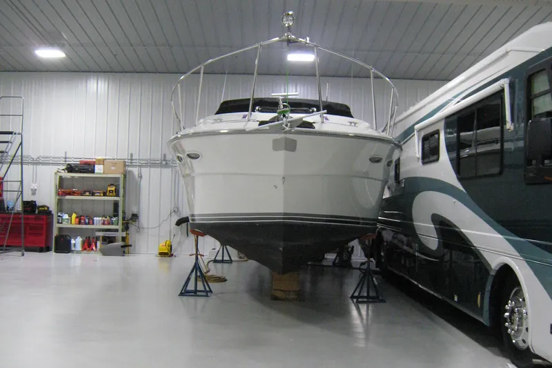 Slide: The Image of 1986 Sea Ray 340 Express Cruiser in storage, alongside a large RV in a garage. - 6