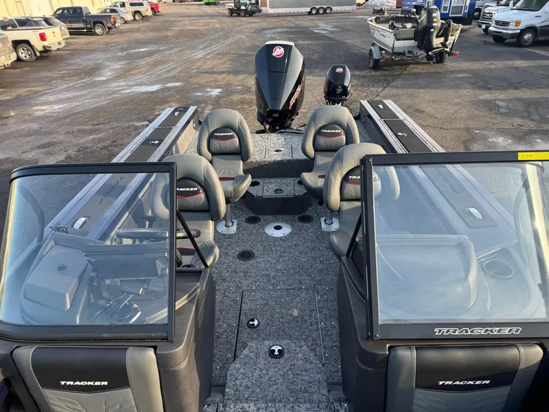 Slide: The Image of 2024 Tracker Targa V-19 WT boat interior with seating and motor, parked outdoors. - 14