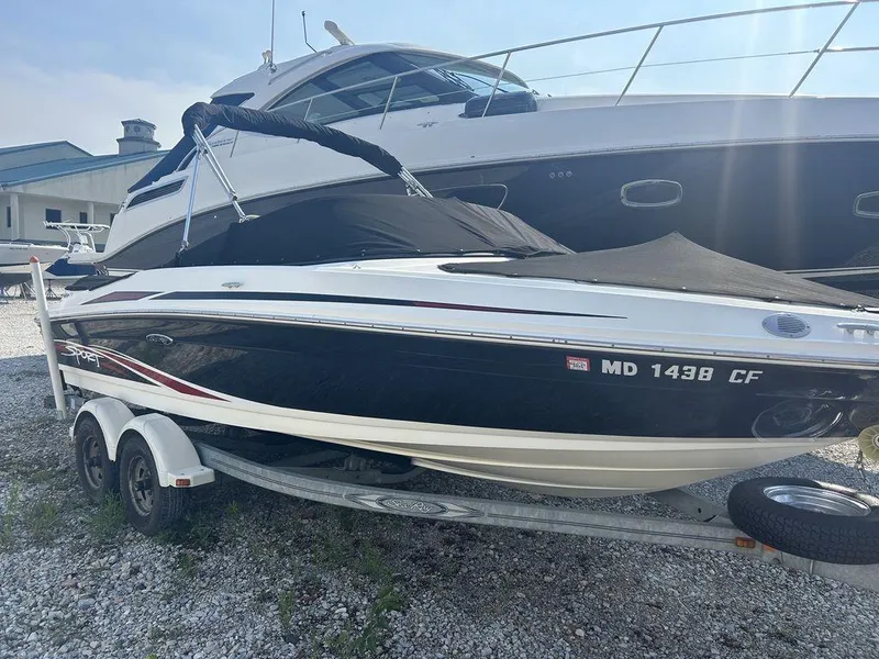 Slide: The Image of 2012 Sea Ray 205 Sport boat on trailer, covered, parked on gravel. - 0