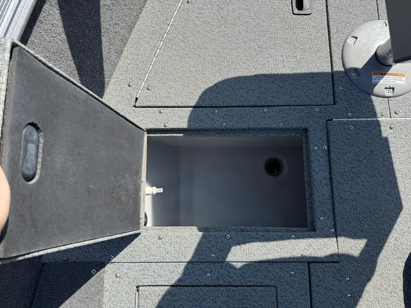 Slide: The Image of 2017 Lund 1650 Rebel XS SS boat storage compartment open, showing interior space. - 14