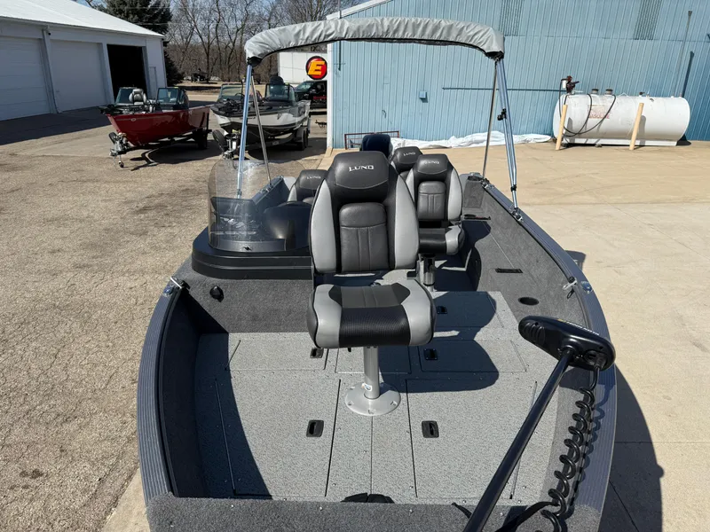 Slide: The Image of 2017 Lund 1650 Rebel XS SS fishing boat with seating and canopy in a marina setting. - 9