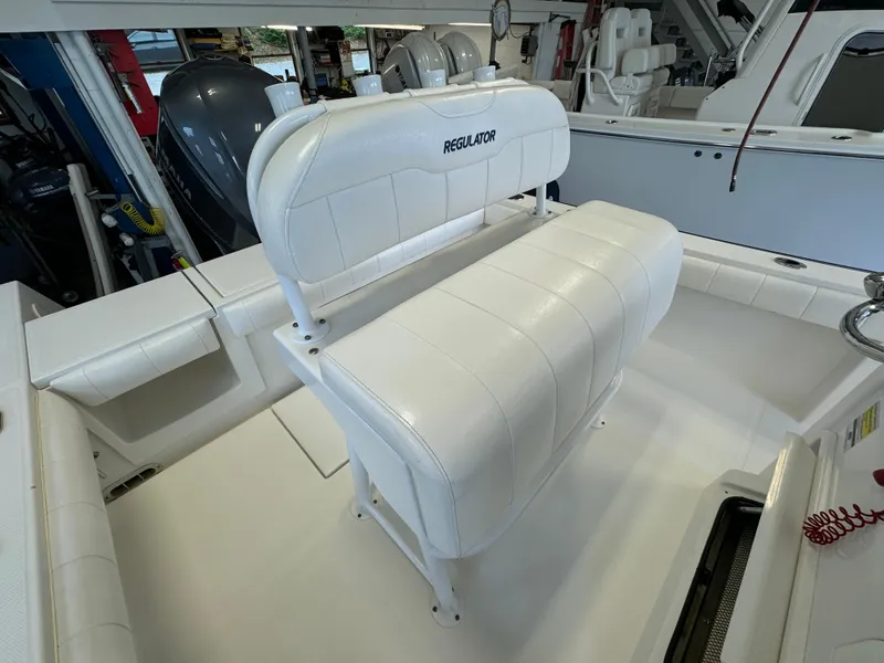 Slide: The Image of 2012 Regulator 24 Forward Seating boat with white cushioned seats in a showroom. - 6