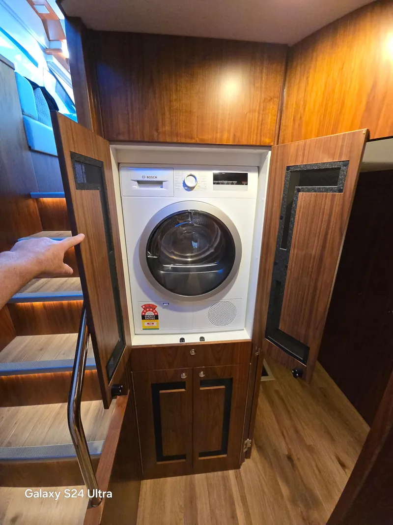 Slide: The Image of Laundry area inside 2022 Riviera 54 Enclosed Flybridge yacht with wooden cabinetry. - 10