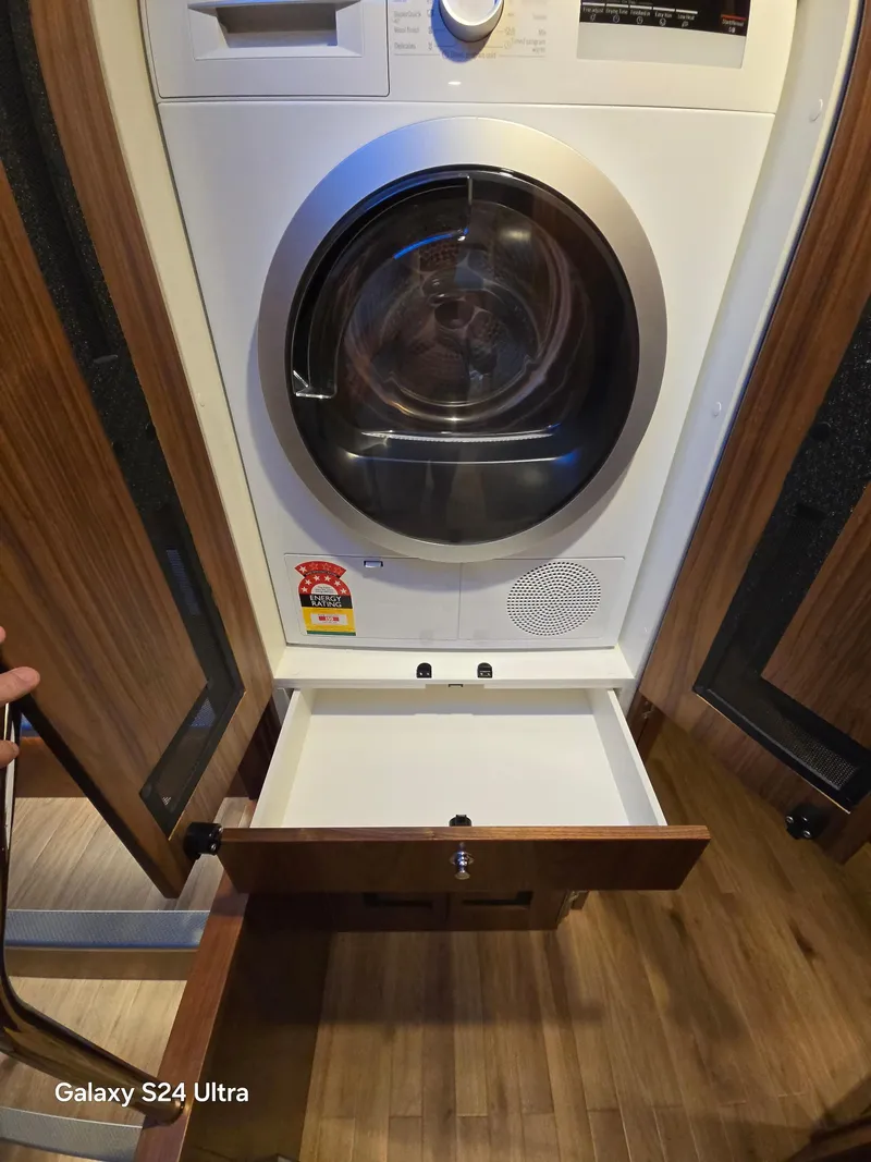 Slide: The Image of 2022 Riviera 54 Enclosed Flybridge laundry area with washer-dryer and open storage drawer. - 11
