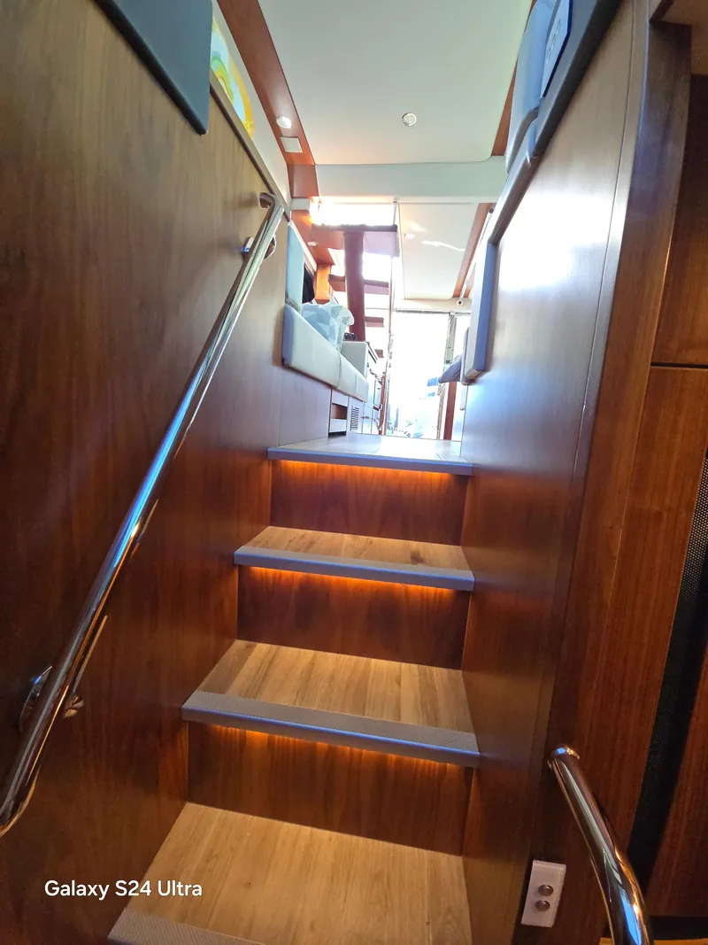 Slide: The Image of Interior stairs of 2022 Riviera 54 Enclosed Flybridge yacht, featuring wooden finish and modern design. - 14