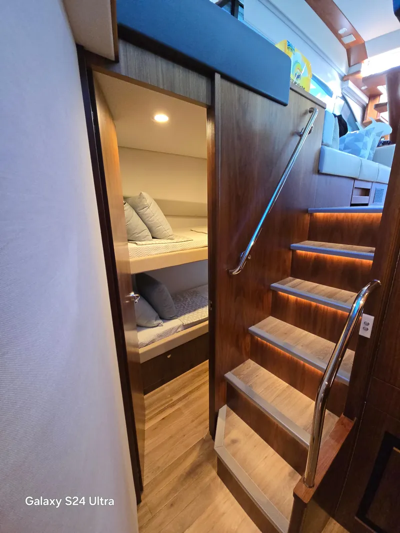 Slide: The Image of 2022 Riviera 54 Enclosed Flybridge interior with wooden stairs and cozy bunk beds. - 15