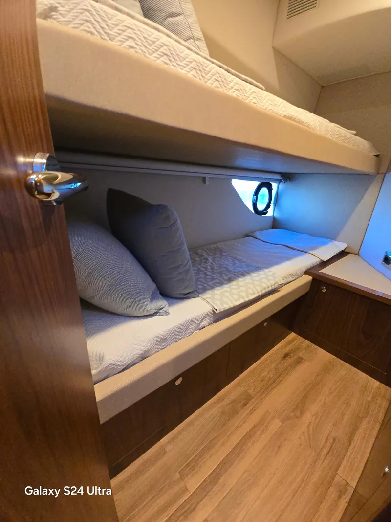 Slide: The Image of Interior cabin of 2022 Riviera 54 Enclosed Flybridge with bunk beds and wooden flooring. - 17