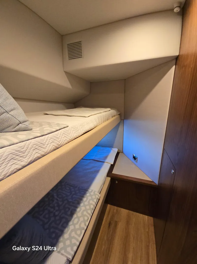 Slide: The Image of Interior of 2022 Riviera 54 Enclosed Flybridge with cozy bunk beds and wooden accents. - 18