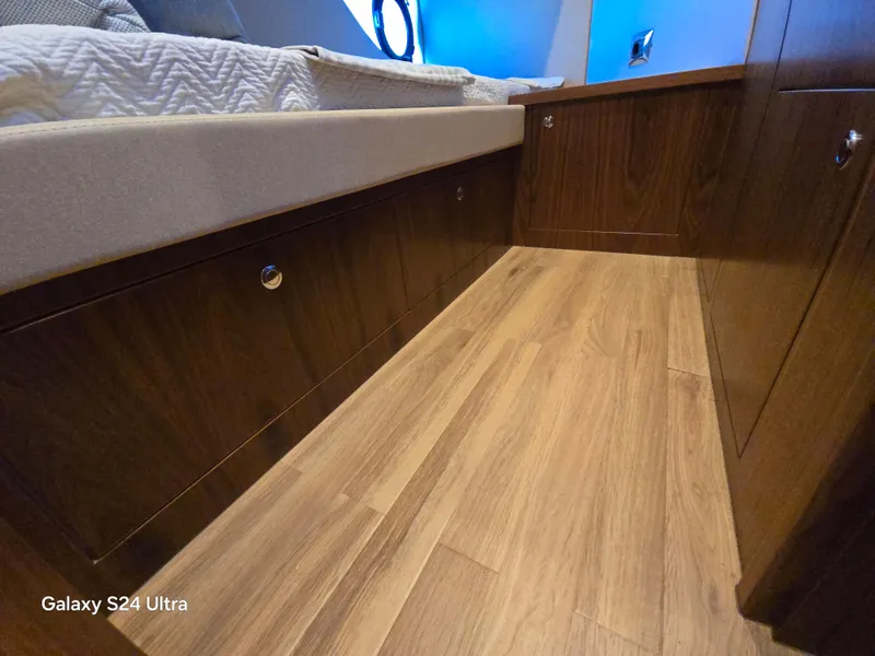 Slide: The Image of 2022 Riviera 54 Enclosed Flybridge interior with wood flooring and storage cabinets. - 19