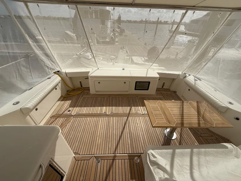 Slide: The Image of 2022 Riviera 54 Enclosed Flybridge yacht interior with teak flooring and seating area. - 2