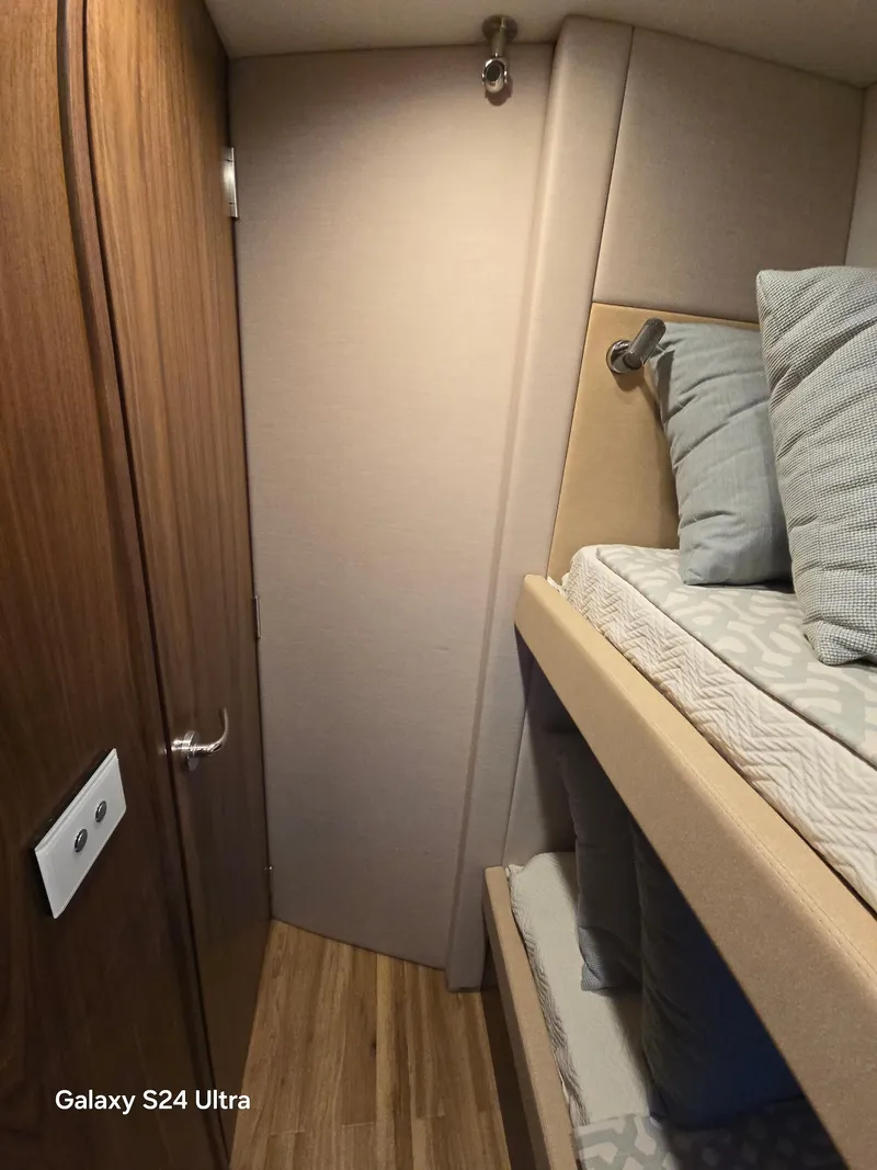 Slide: The Image of 2022 Riviera 54 Enclosed Flybridge cabin with bunk beds and wooden accents. - 20