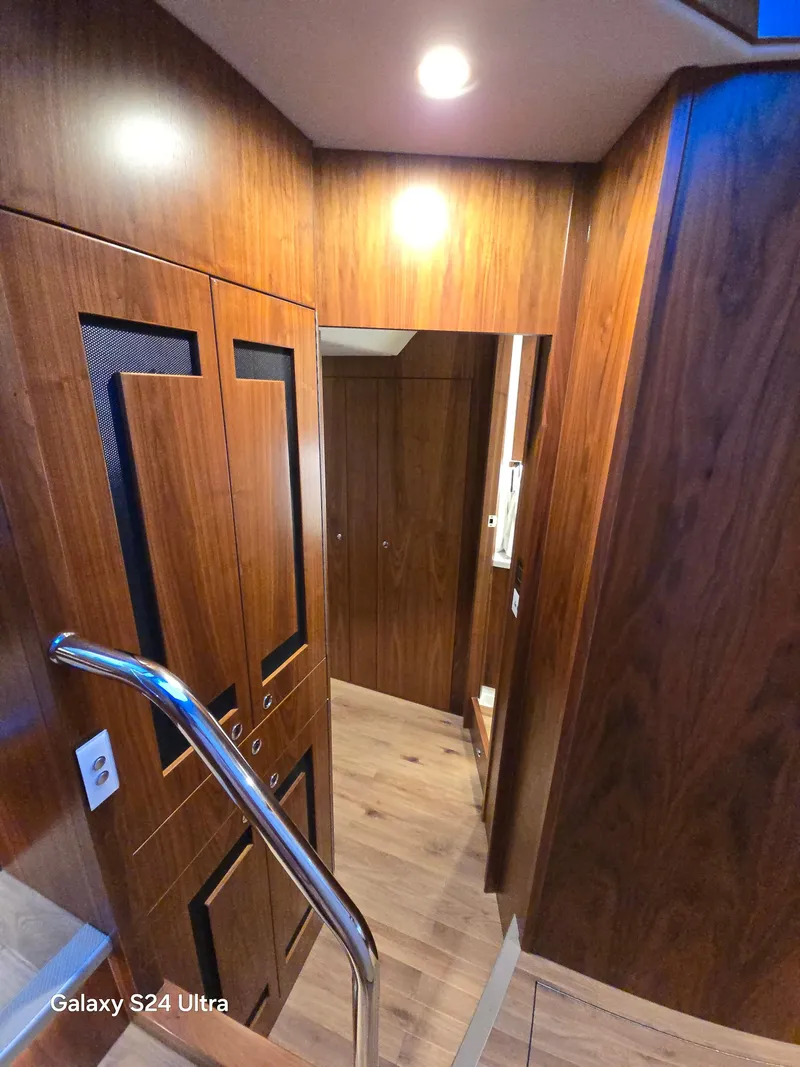 Slide: The Image of Interior of 2022 Riviera 54 Enclosed Flybridge with wooden finishes and modern lighting. - 25