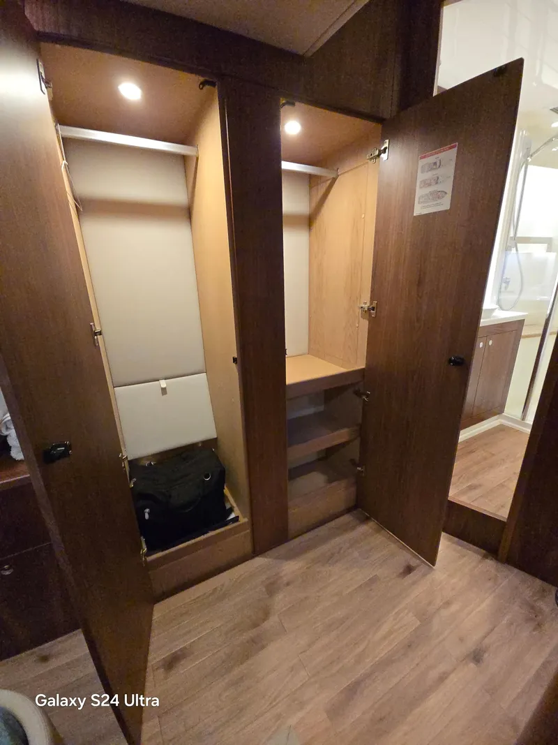 Slide: The Image of Interior view of 2022 Riviera 54 Enclosed Flybridge wardrobe with open wooden doors. - 32