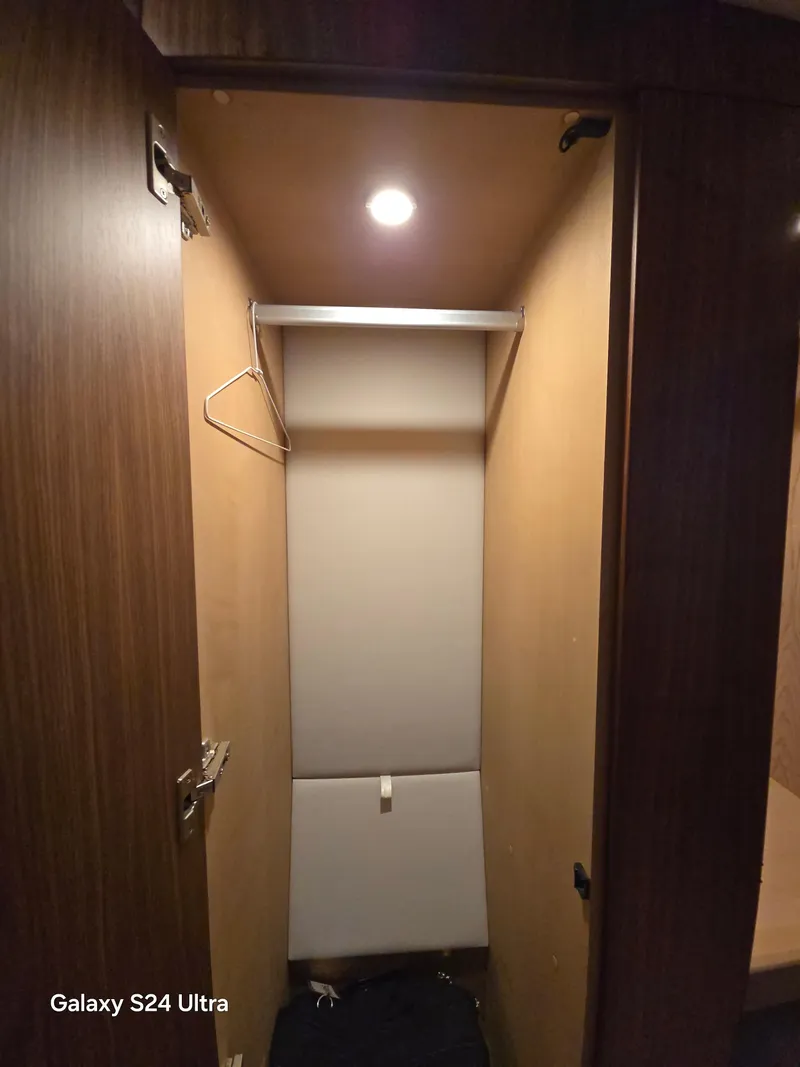 Slide: The Image of Closet interior in 2022 Riviera 54 Enclosed Flybridge yacht, wooden finish, overhead light. - 33