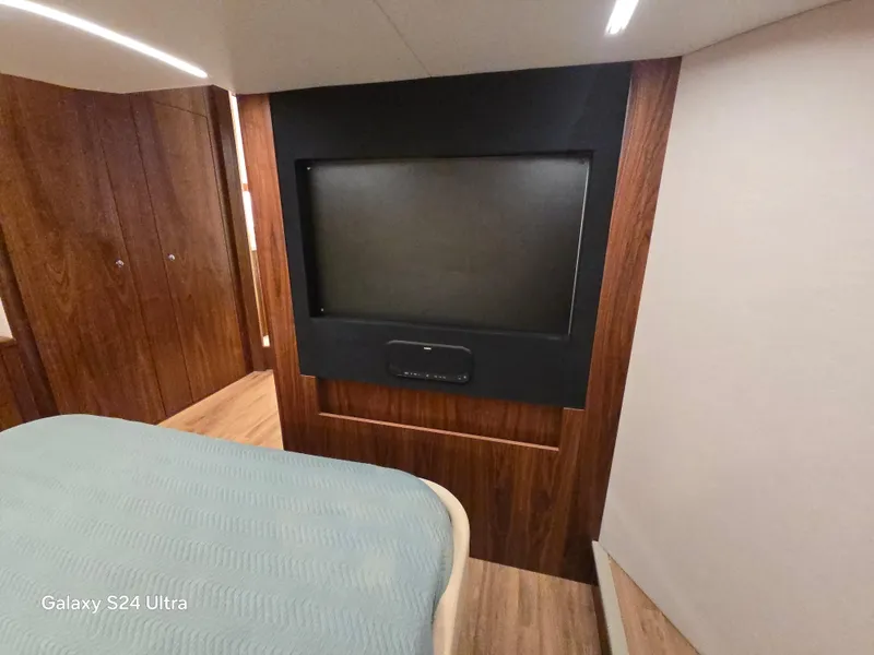 Slide: The Image of Interior of 2022 Riviera 54 Enclosed Flybridge with wood paneling and a mounted TV. - 44
