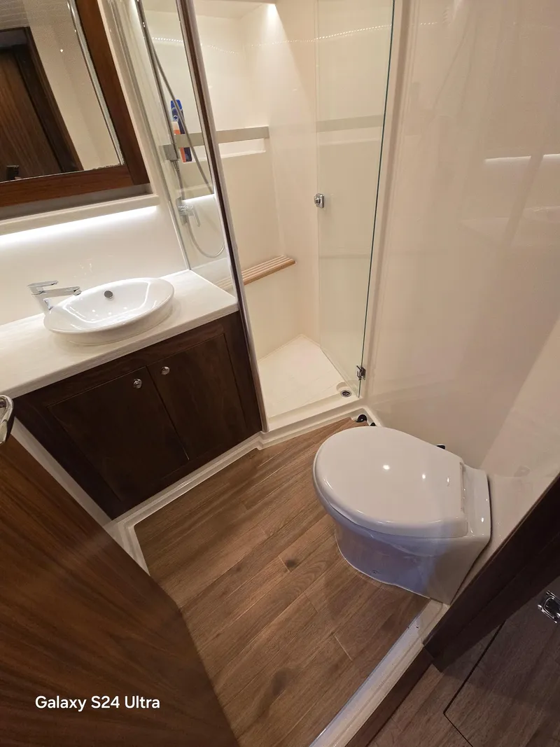 Slide: The Image of 2022 Riviera 54 Enclosed Flybridge bathroom with modern fixtures and wooden flooring. - 7