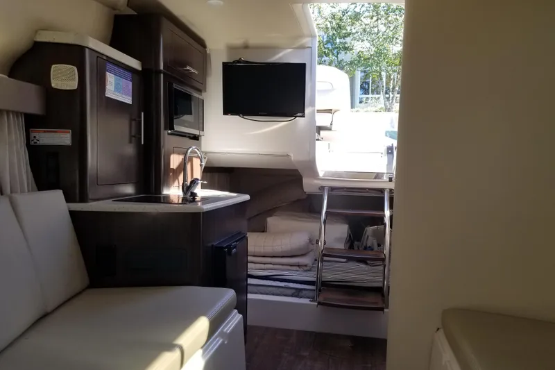 Slide: The Image of 2018 Regal 28 Express cabin interior with kitchenette, seating, and TV. - 11