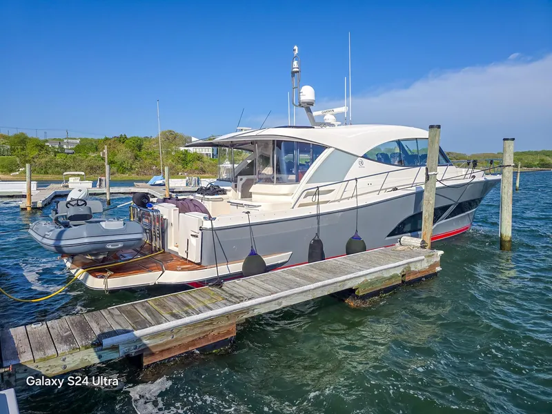 Slide: The Image of 2022 Riviera 505 SUV yacht docked at marina, clear sky, calm water. - 0