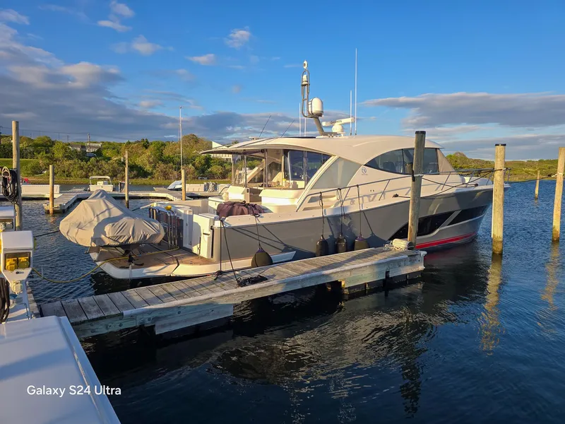 Slide: The Image of 2022 Riviera 505 SUV yacht docked at marina under clear blue sky. - 1