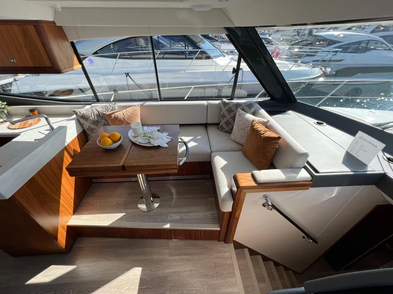 Slide: The Image of 2022 Riviera 505 SUV interior with elegant seating and dining area, overlooking marina. - 27