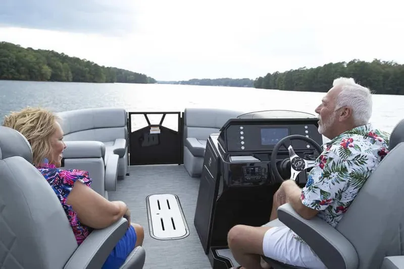 Slide: The Image of 2025 Veranda Vertex 22RC pontoon boat cruising on a scenic lake with two passengers. - 6
