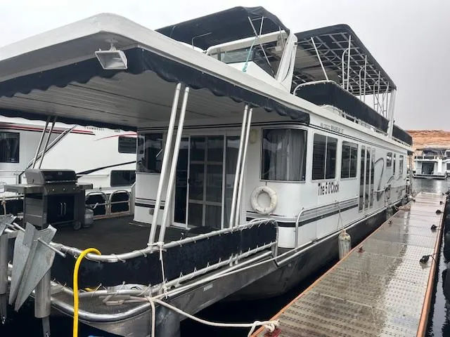 Slide: The Image of 2007 Lakeview houseboat docked, featuring spacious deck and upper seating area. - 2