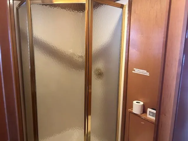 Slide: The Image of Shower area in 2007 Lakeview houseboat with frosted glass door and wooden paneling. - 8