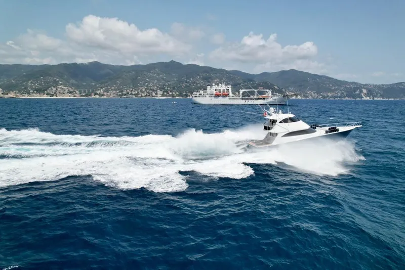 Slide: The Image of 2018 Viking 62 Enclosed Bridge yacht cruising on open sea with scenic coastline backdrop. - 10