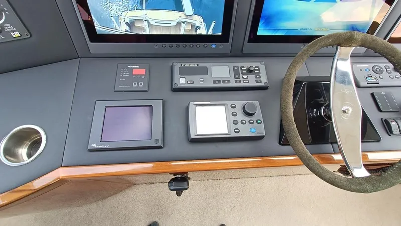 Slide: The Image of Control panel of 2018 Viking 62 Enclosed Bridge yacht with navigation screens and steering wheel. - 25