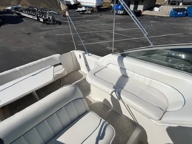 Slide: The Image of 1996 Sea Ray 270 Sundancer boat interior with white seating in a parking lot. - 11