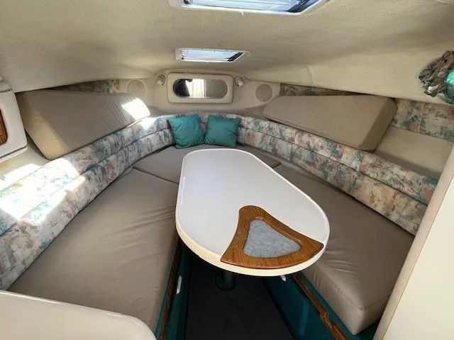 Slide: The Image of 1996 Sea Ray 270 Sundancer cabin interior with cushioned seating and table. - 14