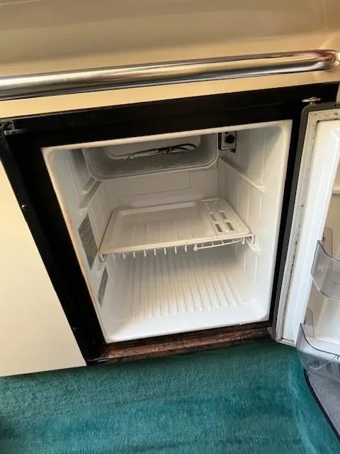 Slide: The Image of Open refrigerator inside 1996 Sea Ray 270 Sundancer boat, showing empty interior and door shelves. - 19