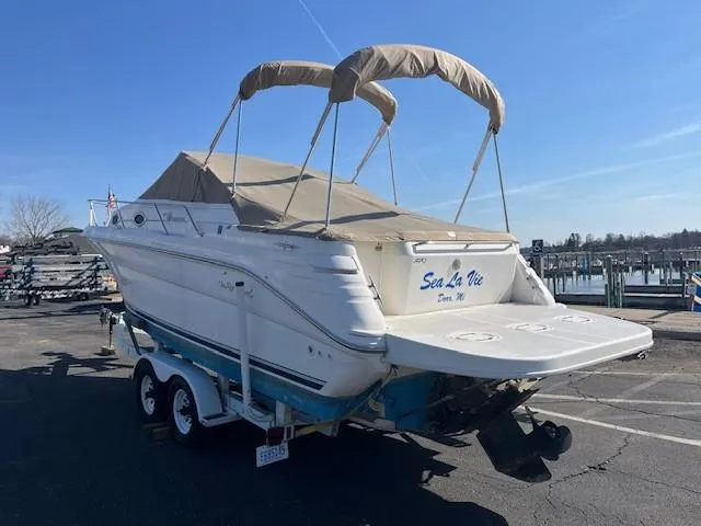 Slide: The Image of 1996 Sea Ray 270 Sundancer boat on trailer, parked outdoors under clear blue sky. - 3
