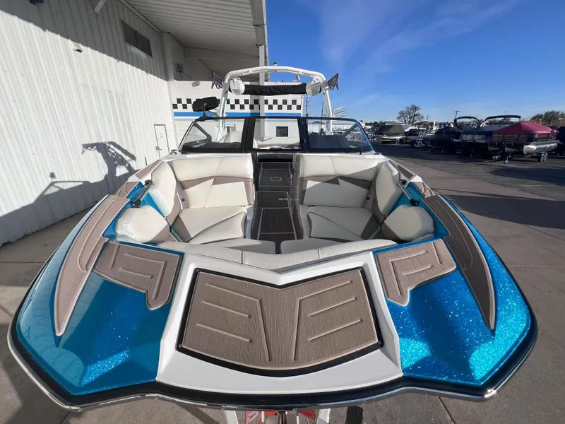 Slide: The Image of 2022 Centurion Fi25 boat with blue accents and spacious seating, docked outdoors. - 2