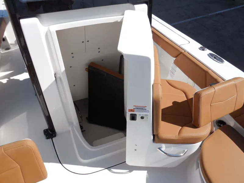 Slide: The Image of 2025 Robalo 246 Cayman boat interior with tan seating and storage compartment. - 11