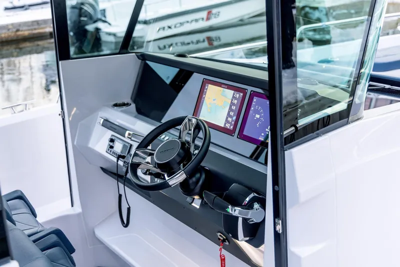 Slide: The Image of 2025 Axopar 29XC Cross Cabin Aft Cabin boat interior with seating and table on a sunny beach. - 7