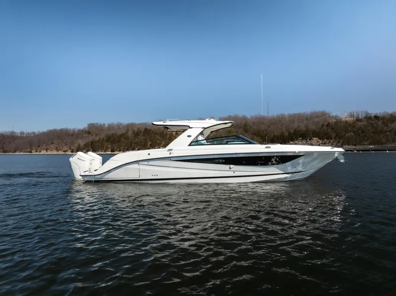 Slide: The Image of 2023 Sea Ray SLX 400 OB boat cruising on a calm lake under a clear blue sky. - 0