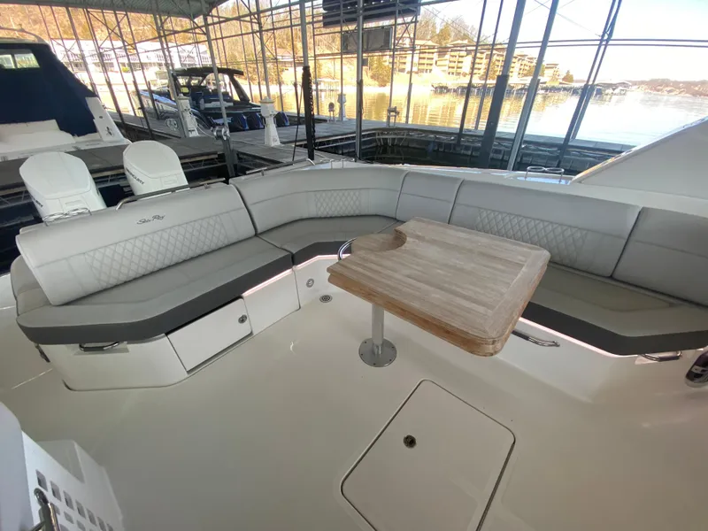 Slide: The Image of 2023 Sea Ray SLX 400 OB boat interior with cushioned seating and wooden table. - 15