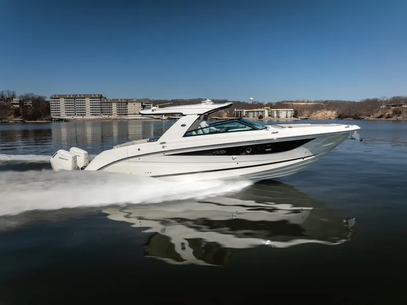 Slide: The Image of 2023 Sea Ray SLX 400 OB cruising on a calm lake with buildings in the background. - 3