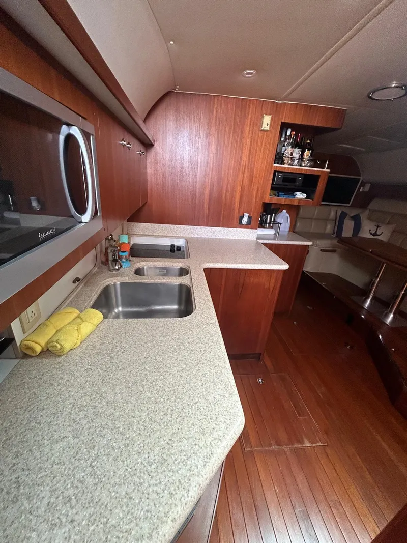Slide: The Image of 2003 Tiara Yachts 4000 Express interior kitchen with wood cabinetry and dual sinks. - 11