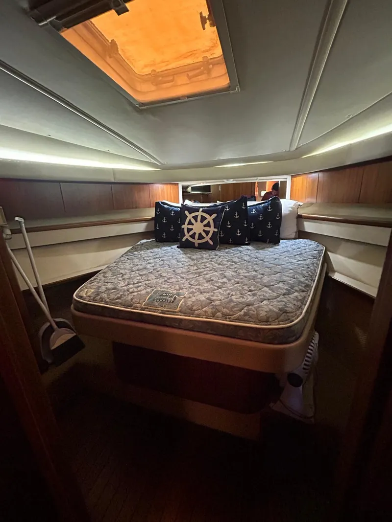 Slide: The Image of 2003 Tiara Yachts 4000 Express cabin with bed, nautical-themed pillows, and overhead lighting. - 12