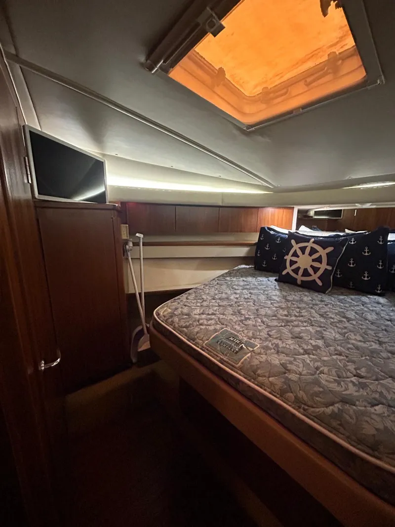 Slide: The Image of 2003 Tiara Yachts 4000 Express cabin with bed, nautical-themed pillows, and overhead hatch. - 13
