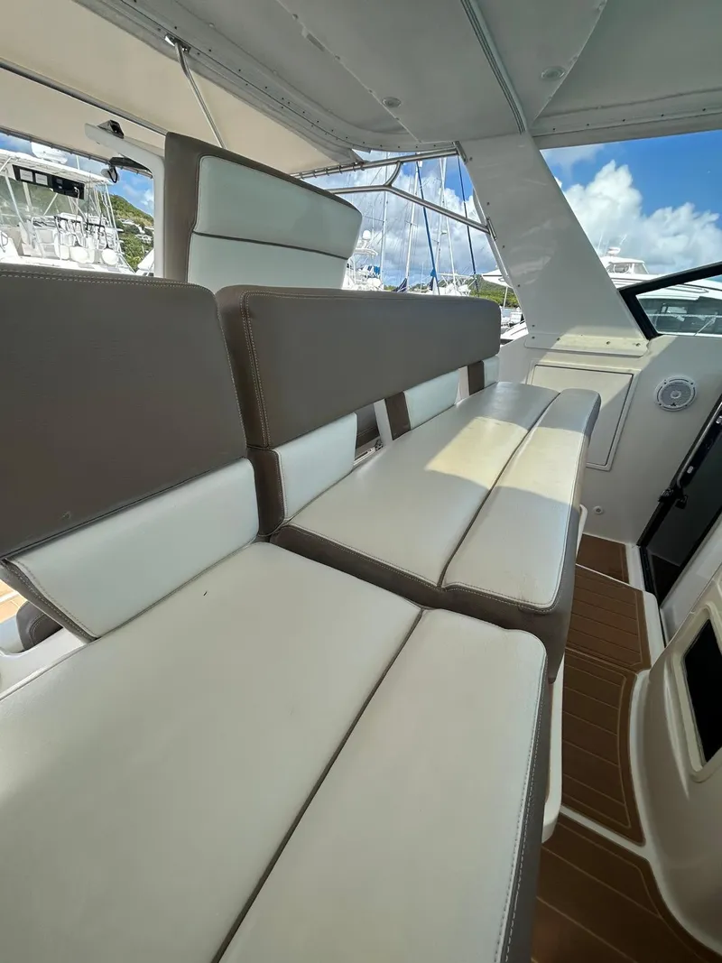 Slide: The Image of 2003 Tiara Yachts 4000 Express interior seating with white and brown cushions, under a sunny sky. - 4