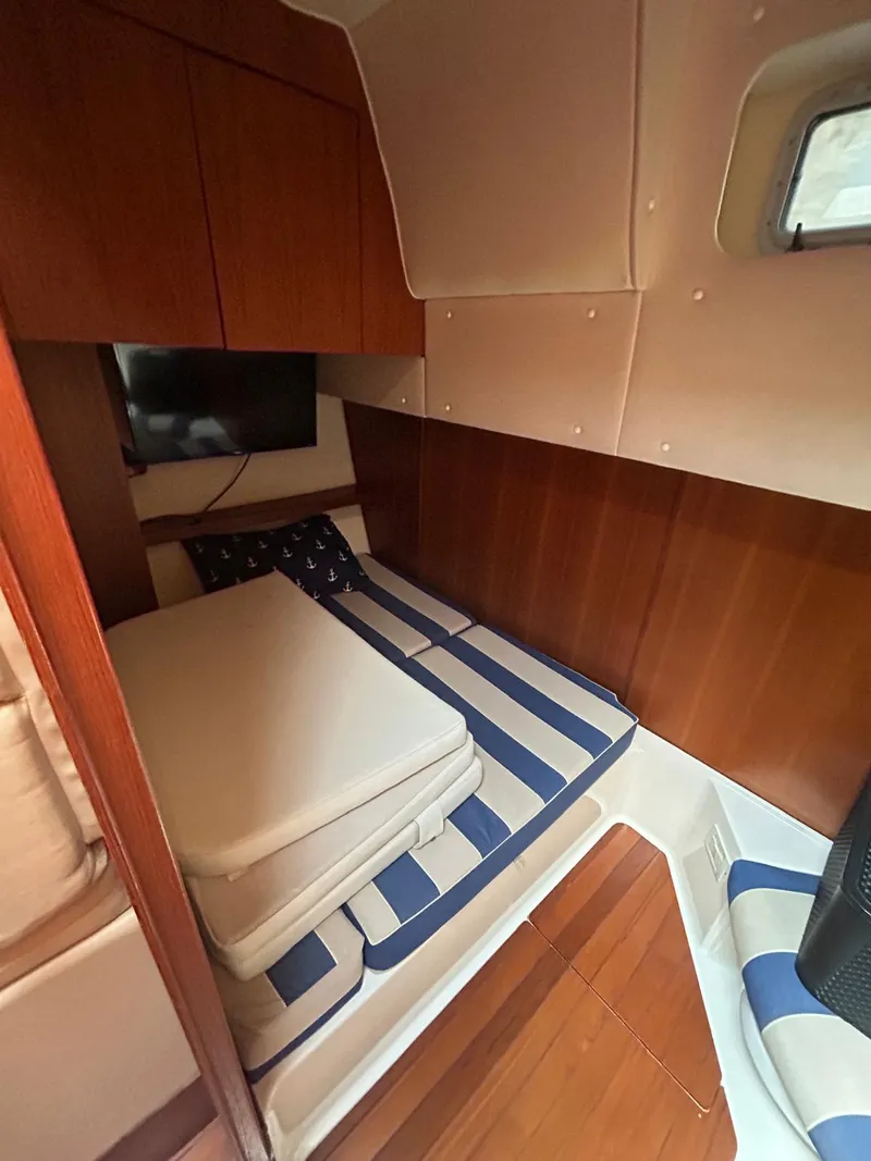Slide: The Image of 2003 Tiara Yachts 4000 Express cabin with striped bedding and wooden interior. - 9
