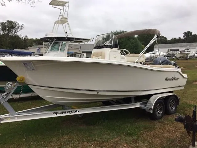 Slide: The Image of 2018 NauticStar 2102 Legacy boat on trailer, parked on grass. - 0