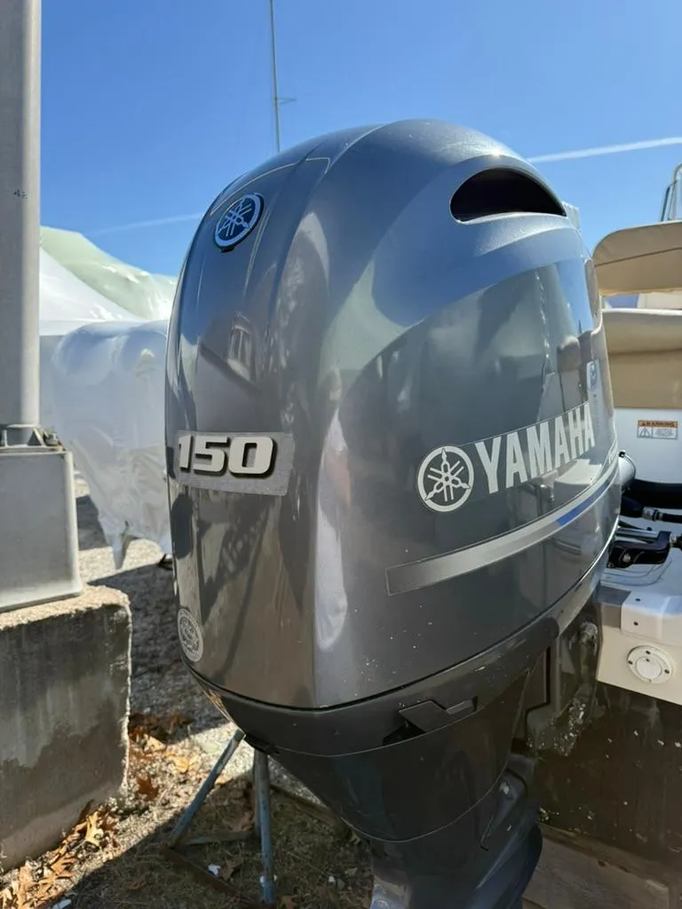 Slide: The Image of 2018 NauticStar 2102 Legacy with Yamaha 150 outboard motor, parked outdoors. - 10