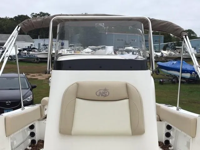 Slide: The Image of 2018 NauticStar 2102 Legacy boat with beige seating and canopy, docked in a marina. - 6