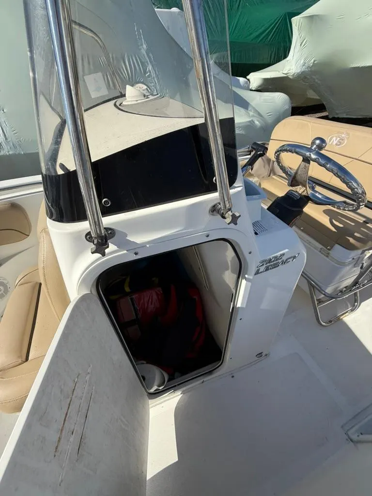Slide: The Image of 2018 NauticStar 2102 Legacy boat interior with open storage compartment and steering wheel. - 8